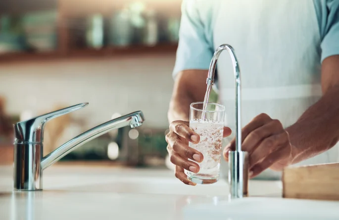 Man getting drinking water from reverse osmosis tap